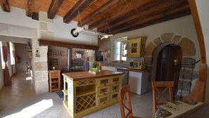 Una cocina rústica con vigas de madera a la vista, una chimenea de ladrillo y una isla de madera con cajones.