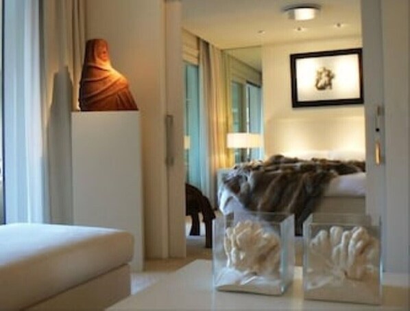 Ein modernes Hotelzimmer mit einem Bett, einem Nachttisch, einer Lampe und einem gerahmten Bild an der Wand.