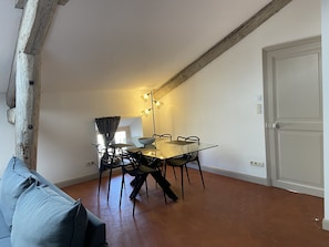 A dining area with a glass table and chairs, a light fixture above, and a door to the right. - Charming apartment in the heart of Avignon (Avignon)