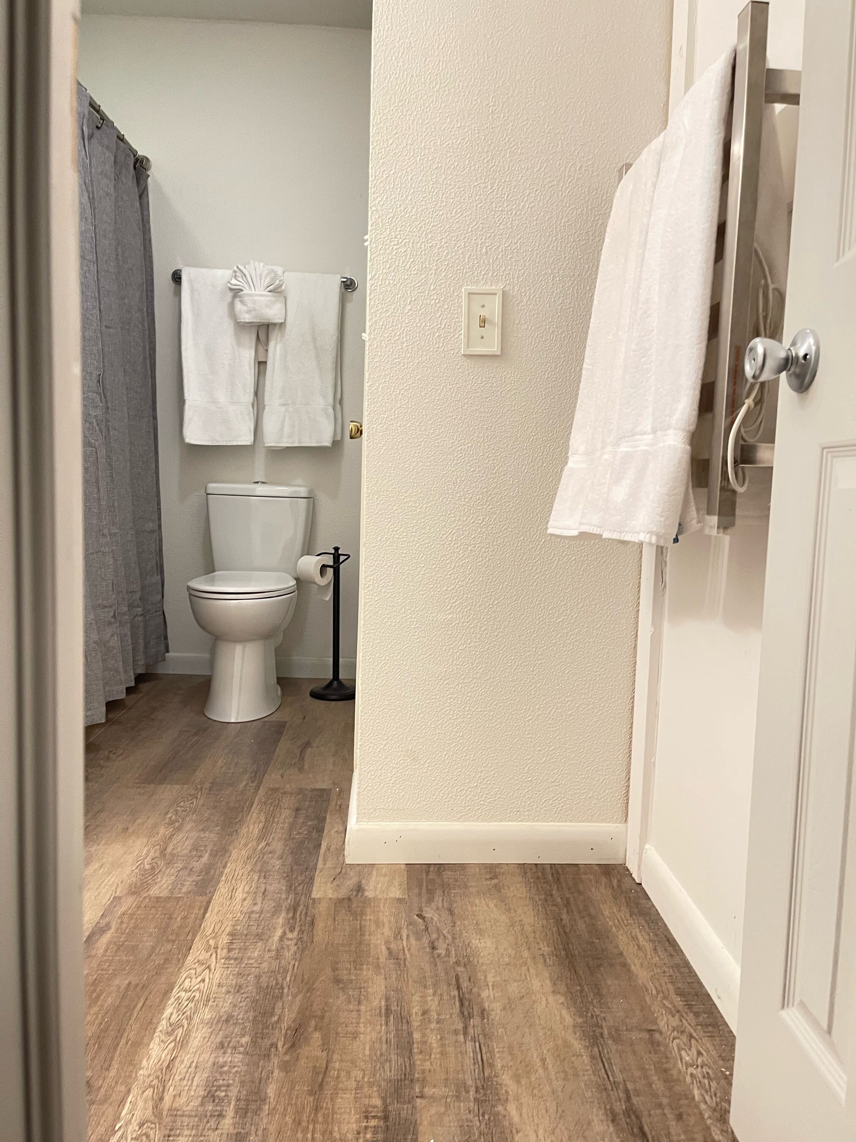 Ein Badezimmer mit Toilette, Handtuchhalter mit Handtuch, Lichtschalter und Tür.