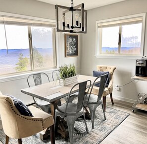 A dining area with a table, chairs, a chandelier, a water dispenser, and a view of the outdoors.