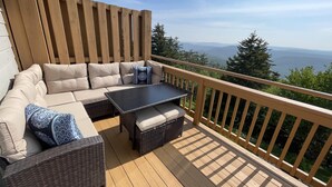 Une terrasse en bois avec un canapé, une table et des chaises en osier.