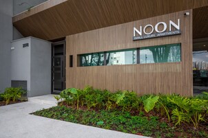 Un edificio moderno con un letrero que dice "NOON SMALL LUXURY APARTMENTS" y el número "2078" en la fachada.