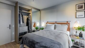 Une chambre moderne avec un grand lit, un dressing, des lampes de chevet et une petite table d’appoint agrémentée d’une plante.