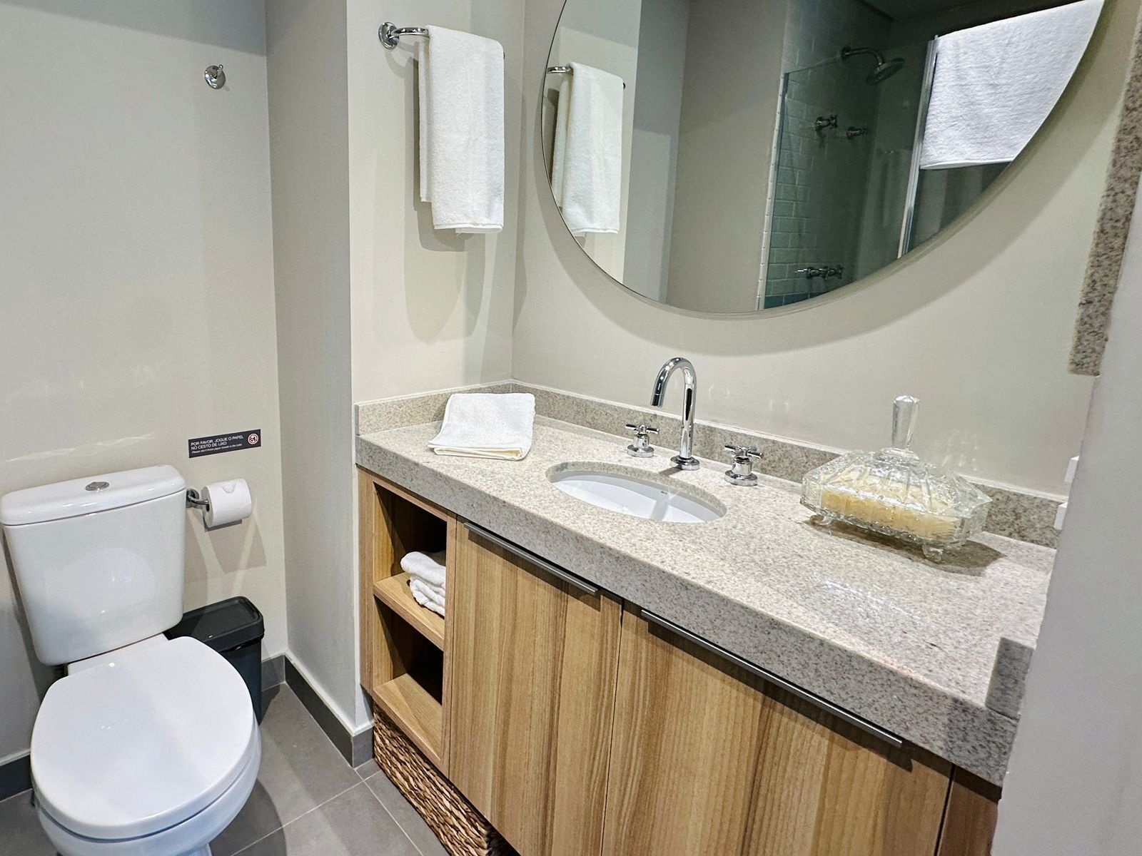 Un baño moderno con inodoro, lavamanos y espejo.