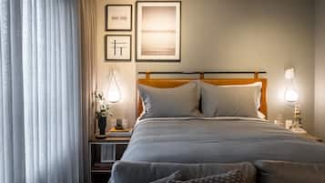 A hotel room with a bed, bedside tables, a table with a bowl and mug, and curtains.