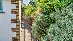 A gated pathway leading to a building with a white facade and exposed brickwork. - Forge Cottage (Padstow)