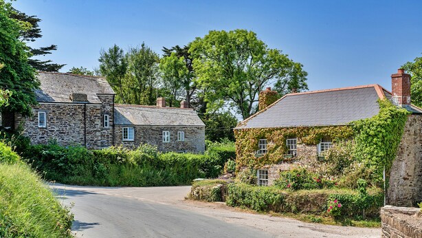 A narrow road flanked by stone houses with ivy-covered walls and a clear blue sky. - Forge Cottage (Padstow)