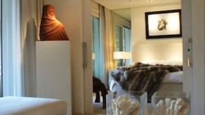 Et moderne hotelværelse med en seng, et natbord, en lampe og et billede i ramme på væggen.