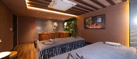 Un cuarto de spa con una camilla de masaje, un rincón de descanso y una cama grande.