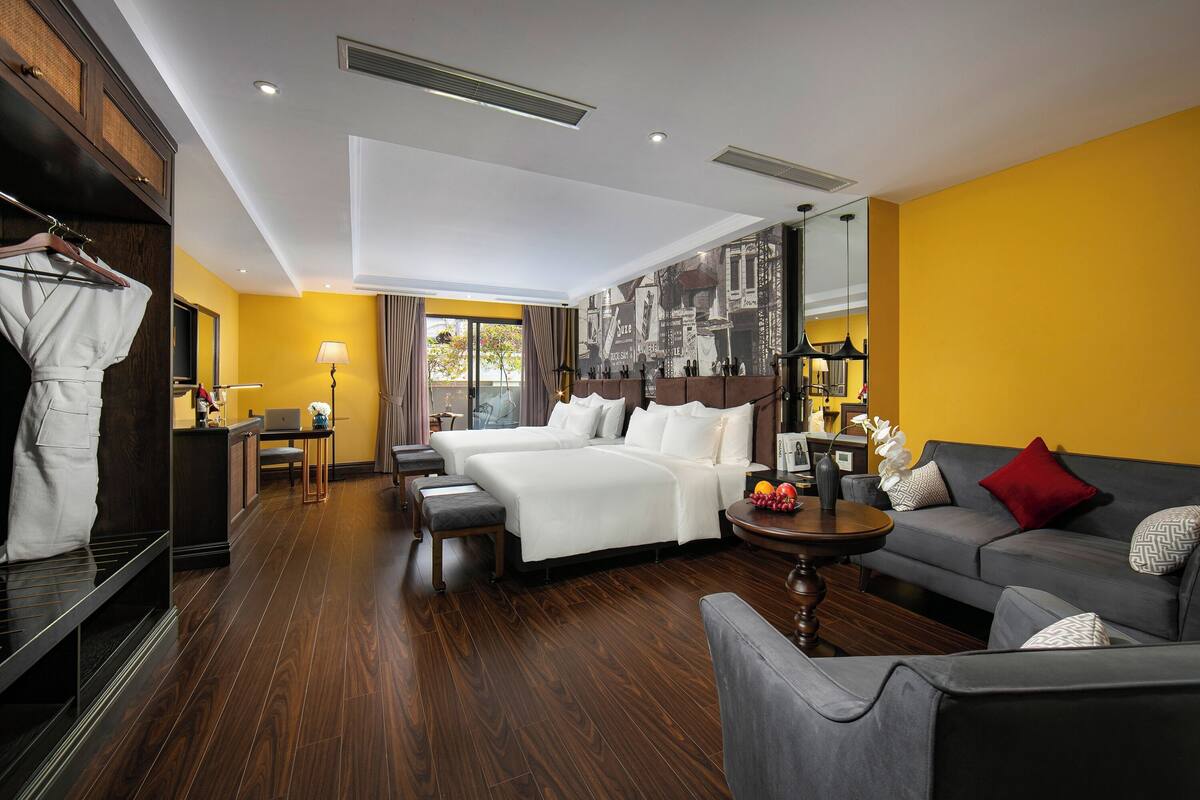 Una habitación de hotel con una cama grande, un sofá, un escritorio y un armario.