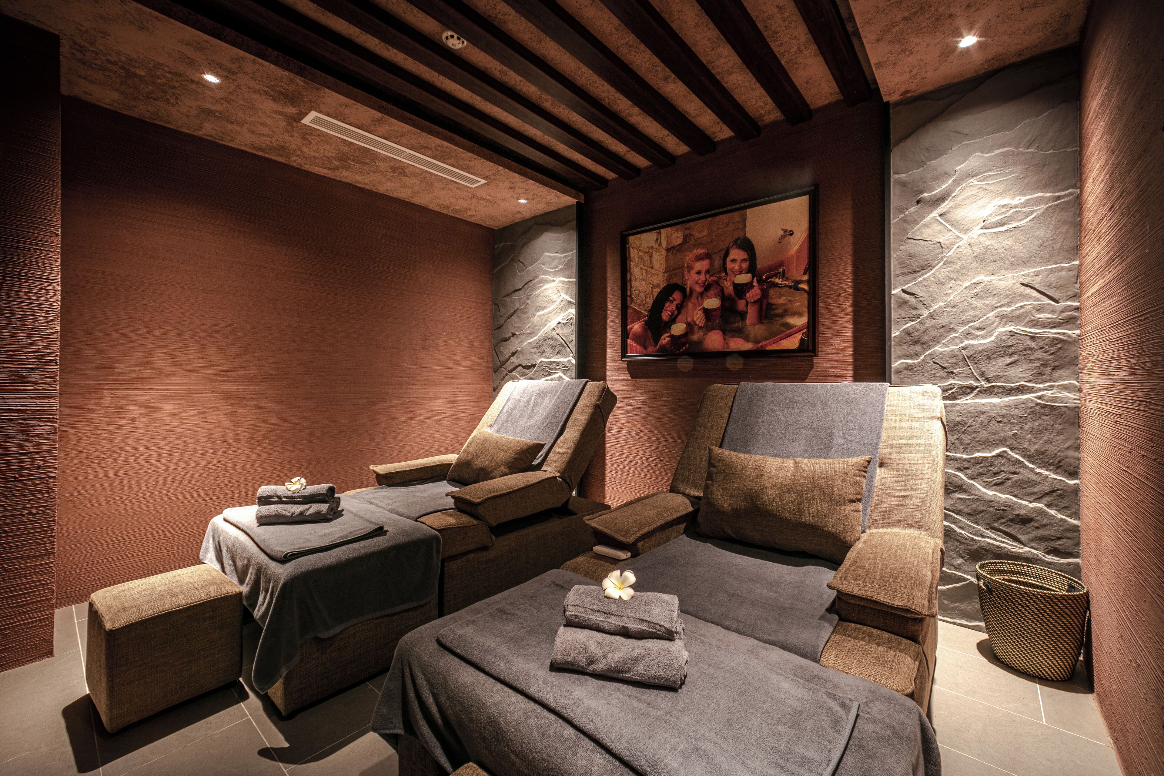 Un cuarto de spa con sillones de masaje, una camilla de masajes y una pared de piedra.