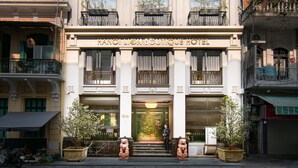 A multi-story building with the sign "HANOI LION BOUTIQUE HOTEL" at the entrance. There are potted plants and a statue of a lion at the front.