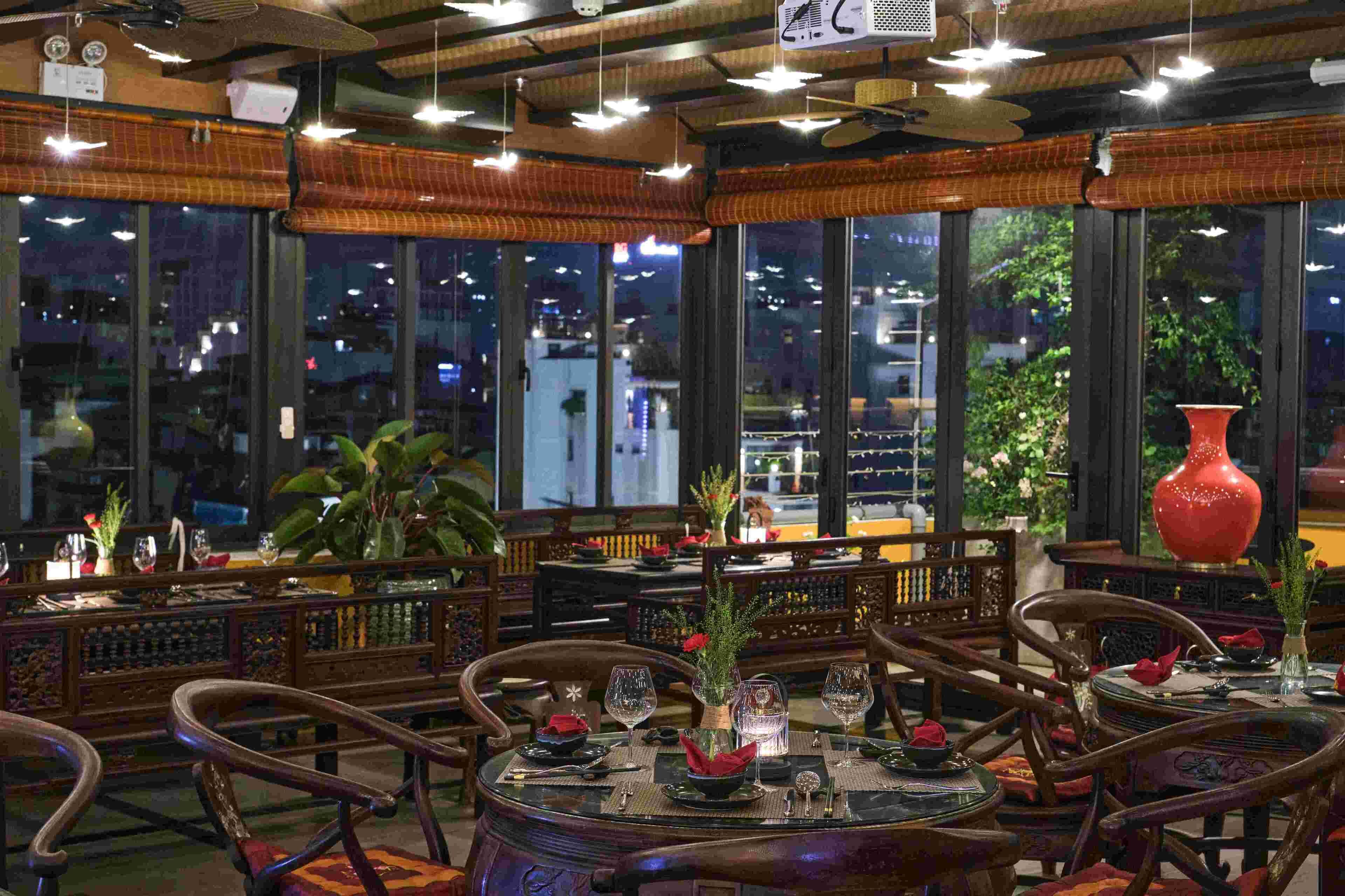 A restaurant with traditional wooden furniture, large windows, and a view of the city at night.