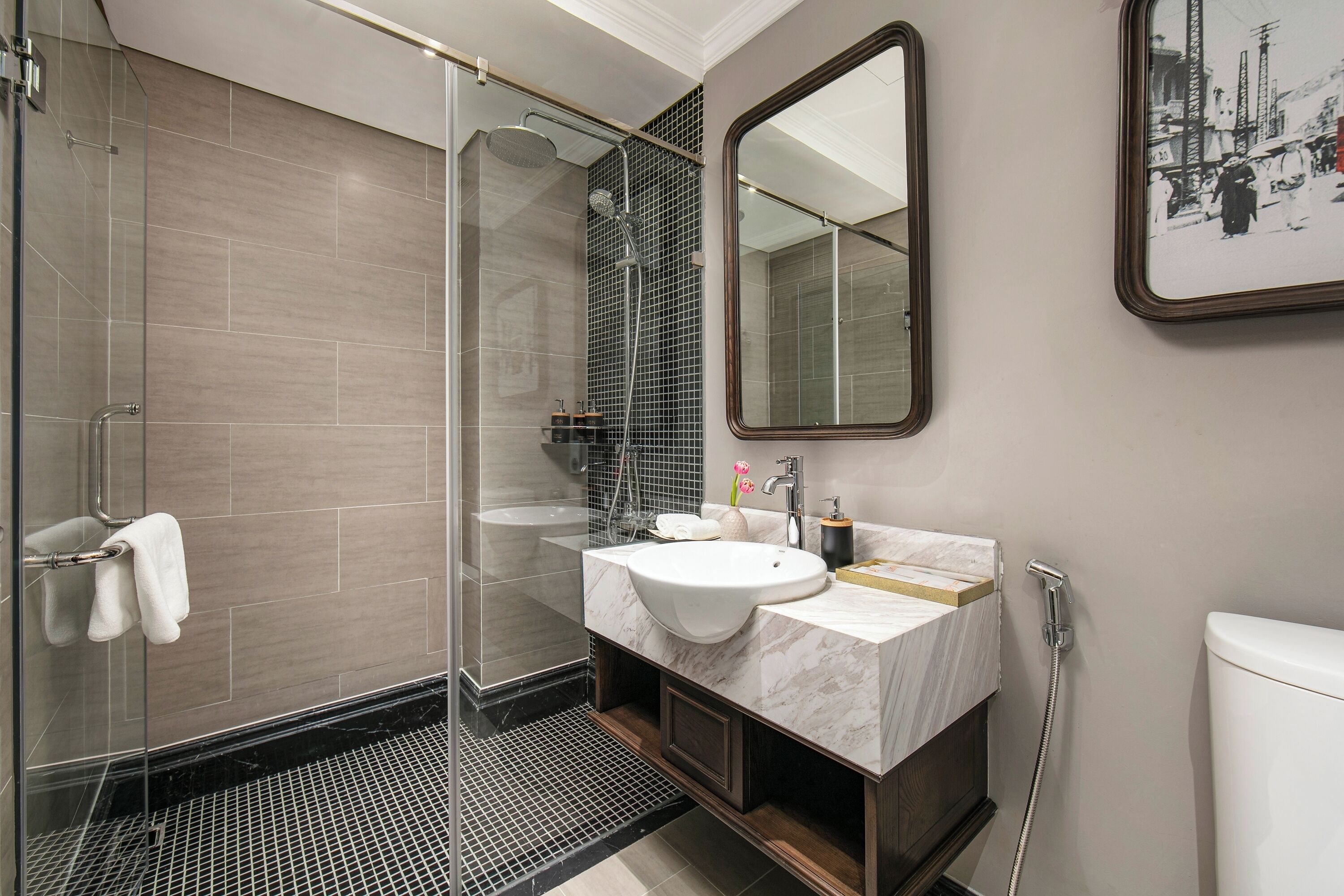 Une salle de bain moderne avec une douche à parois de verre, un lavabo en marbre et un grand miroir.