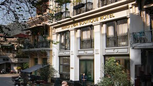 A building with a sign reading "HANOI BOUTIQUE HOTEL" and a statue of a lion in front.