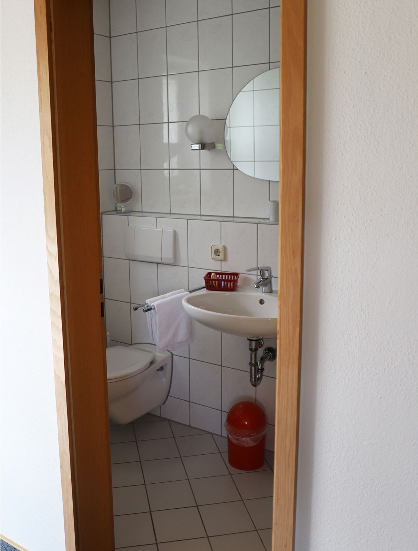 Ein kleines, sauberes Badezimmer mit Toilette, Waschbecken und Spiegel.