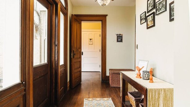 Un passadís amb portes de fusta, una catifes, una console amb objectes decoratius i quadres a la paret.