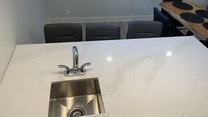 A kitchen with a white marble countertop, a stainless steel sink, and three pendant lights. - Luxury 2 bedroom house - fully renovated - full feature (Richmond Hill)