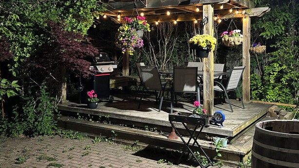 A wooden pergola with string lights, outdoor furniture, and hanging flower baskets in a garden setting. - Luxury 2 bedroom house - fully renovated - full feature (Richmond Hill)