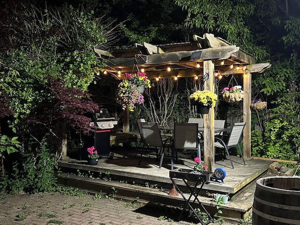 A wooden pergola with string lights, outdoor furniture, and hanging flower baskets in a garden setting. - Luxury 2 bedroom house - fully renovated - full feature (Richmond Hill)