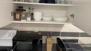 A kitchen with white cabinets, a black microwave, and a dish rack. - Luxury 2 bedroom house - fully renovated - full feature (Richmond Hill)