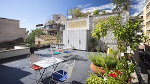 A rooftop patio with outdoor furniture, potted plants, and a view of the cityscape. - Architect designed studio (EP7L). Green rooftop! (Athina)