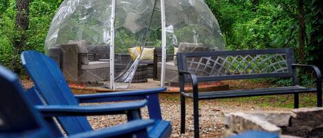 Una estructura abovedada transparente con asientos en su interior, rodeada de árboles.
