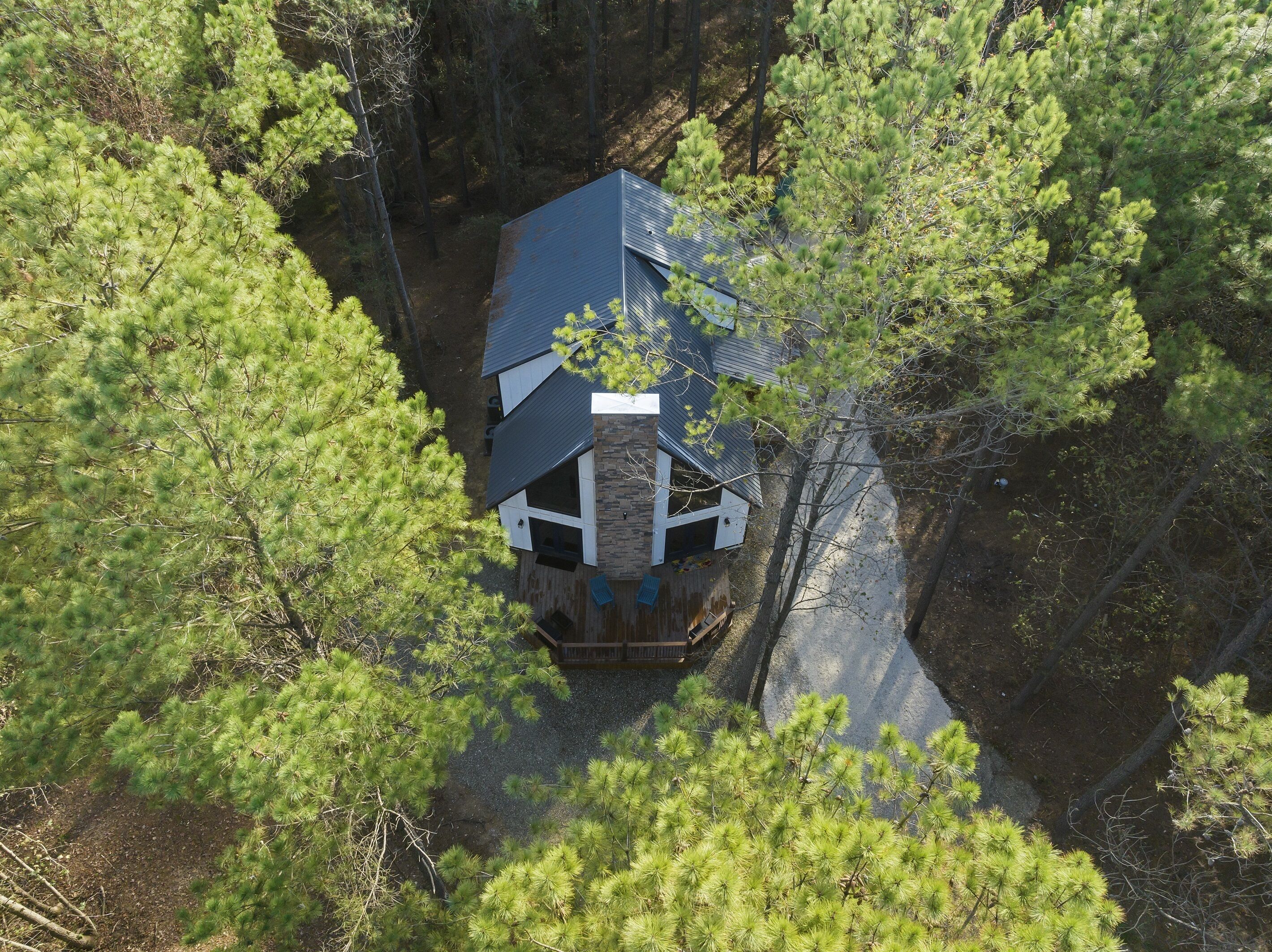 A cabin surrounded by dense pine trees, with a sloped roof and a stone foundation.