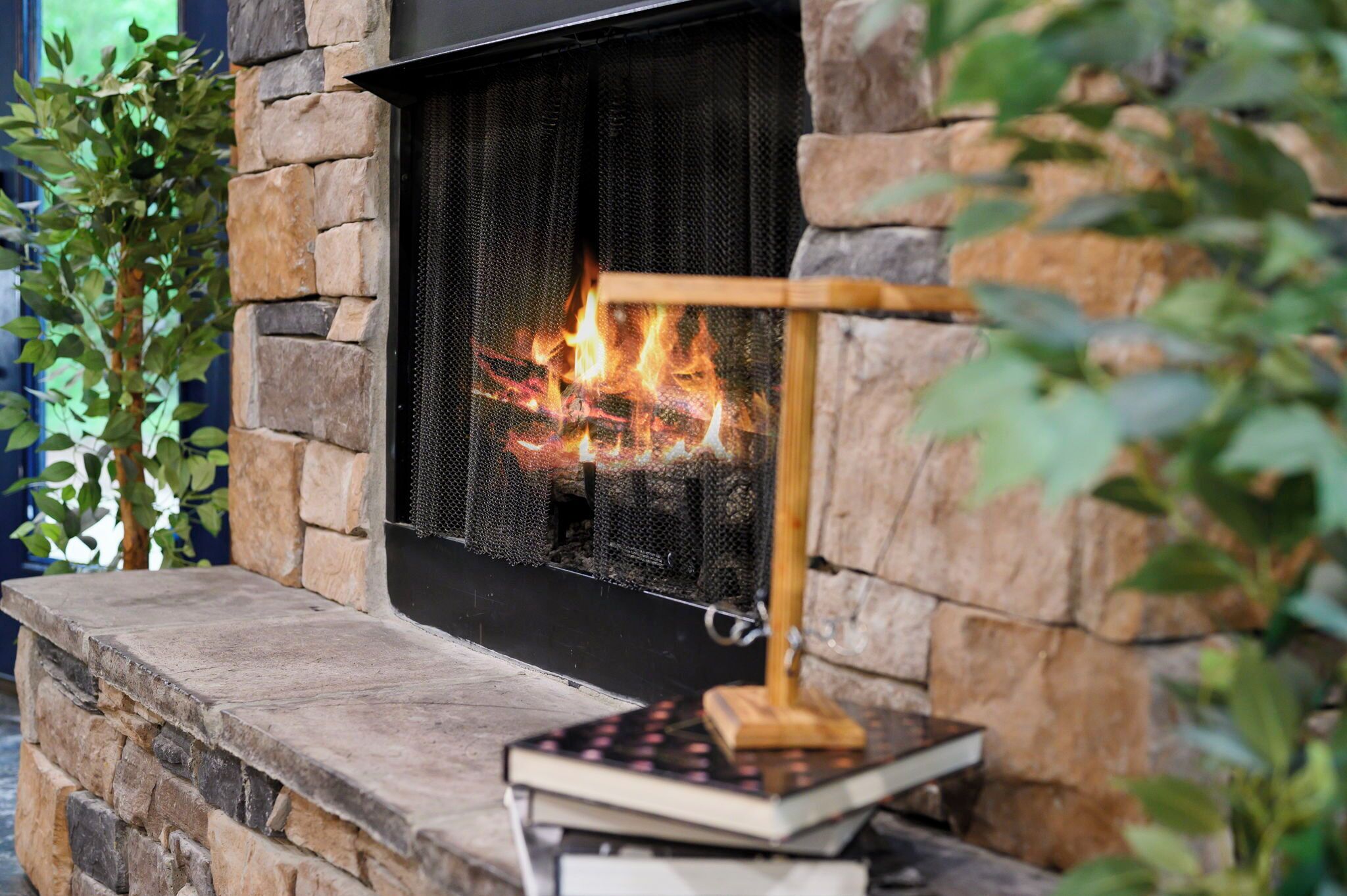 A stone fireplace with a fire, a wooden stand, and a book.