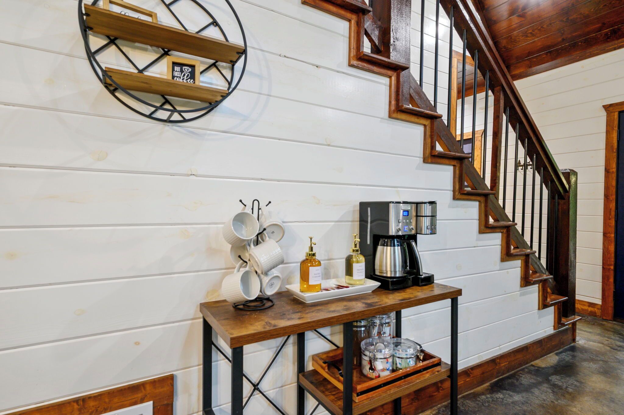 A wooden staircase with a coffee station featuring mugs, a coffee maker, and condiments.