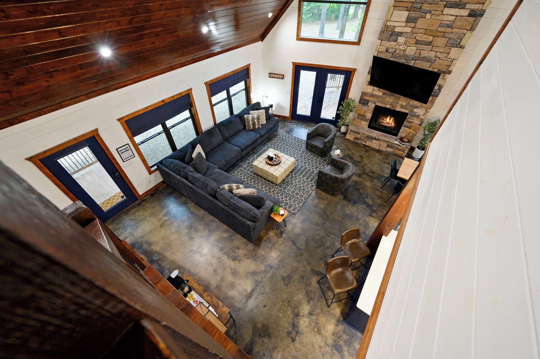 A spacious living area with a dark-colored sofa set, a fireplace, and a stone accent wall.