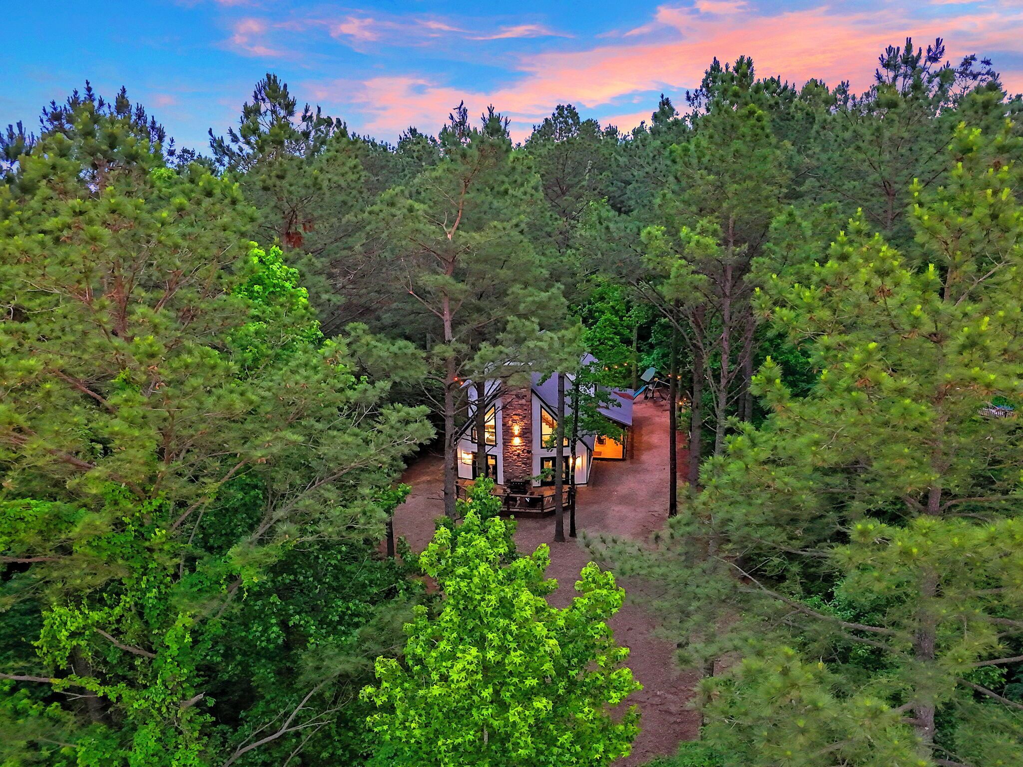 A lodge nestled in a forest with a stone exterior and multiple rooms.