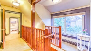 A hallway with wooden railings, a staircase, and a large window with a view of greenery outside. - The Lovemore Grand Retreat (Delta)
