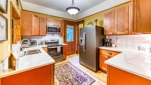 A kitchen with wooden cabinets, a stainless steel refrigerator, a microwave, and a sink. - The Lovemore Grand Retreat (Delta)