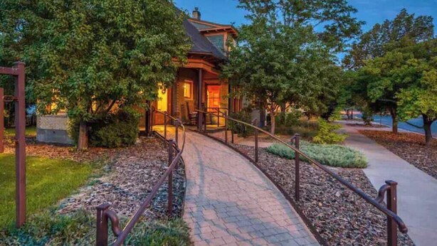 A rustic cabin with a wooden exterior, surrounded by lush greenery and a paved pathway leading to it. - The Lovemore Grand Retreat (Delta)
