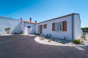 Une maison de plain-pied avec un toit en pente, une antenne parabolique et une allée gravillonnée.