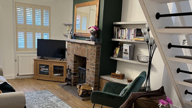 Uma sala de estar com lareira, televisão, estante de livros e um espaço de refeições com mesa e cadeira.