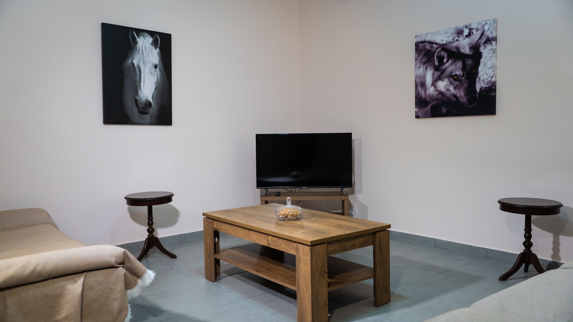 A living room with a wooden table, a TV, and two side tables.