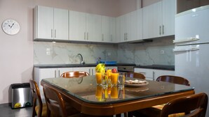 A modern kitchen with white cabinets, a marble backsplash, and a glass dining table. - Andromachis Moneto Under Meteora (Kalabaka)