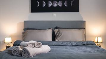 Una cama bien hecha con toallas enrolladas, un calendario de fases lunares en la pared y dos lámparas de noche.