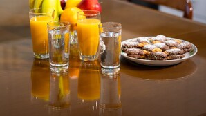 A dining table with fruit, juice glasses, and a plate of pastries in a kitchen. - Andromachis Moneto Under Meteora (Kalabaka)