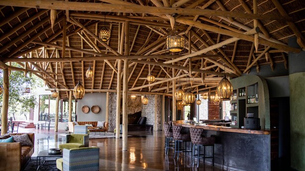 Eine geräumige Lobby mit hoher Holzbalkendecke, einer Bar und bequemen Sitzgelegenheiten.