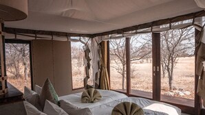 Ein geräumiges Schlafzimmer mit zwei Betten, großen Fenstern und einer Pendelleuchte.