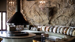 A cozy living room with a stone wall, a round seating area, and a large fireplace.