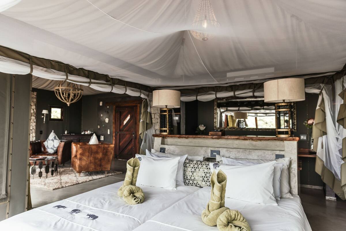 Ein geräumiges Schlafzimmer mit einem großen Bett, einem hölzernen Kopfende und einer Kristallleuchtre.