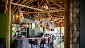 Eine Bar mit Holzbalken, kugelförmigen Pendelleuchten und einer Bar, komplett mit Hockern.
