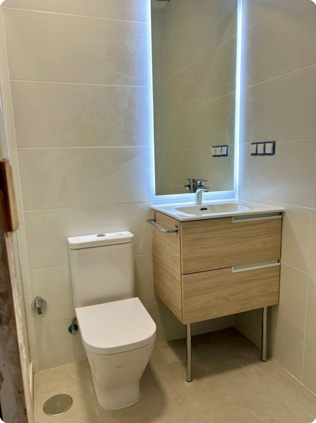 A bathroom with a toilet, a sink, and a mirror.