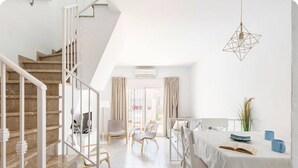 Un interior moderno con una escalera, un comedor y vistas a través de un ventanal.