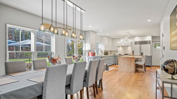 Een moderne keuken met witte kasten, een houten keukeneiland en hanglampen.